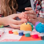 female-hand-making-cartoon-faces-using-colorful-clay